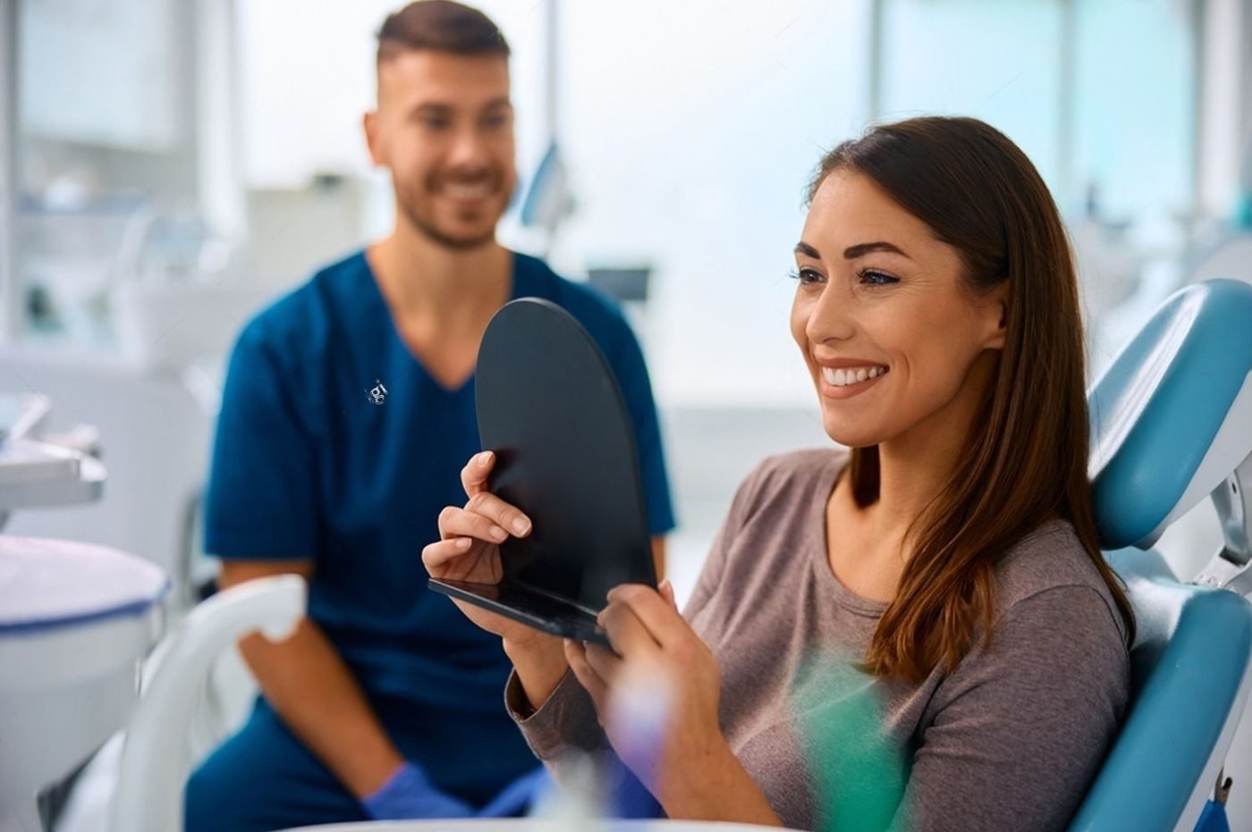 A smiling patient checking her teeth in a mirror