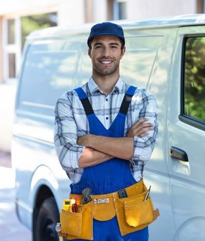 A smiling handyman standing by his van