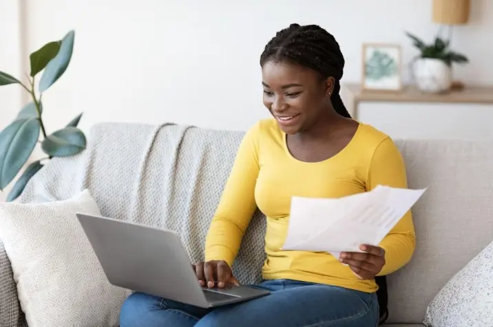 Woman reviewing paperwork on her laptop